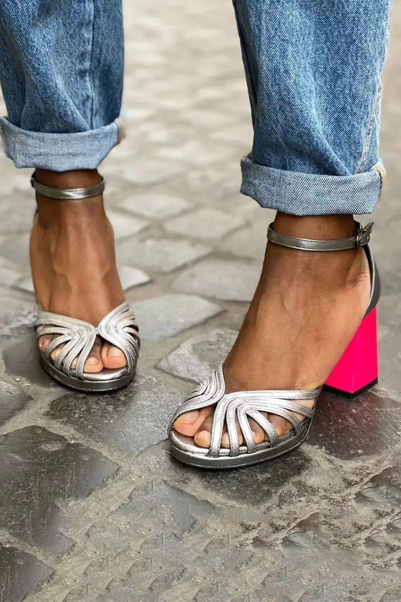 Woman modelling glossy fuchsia heeled sandals with buckle strap on a plain background.