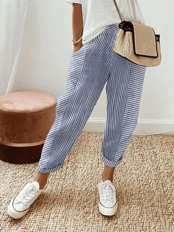 Female model wearing striped trousers with a relaxed fit against a plain background.