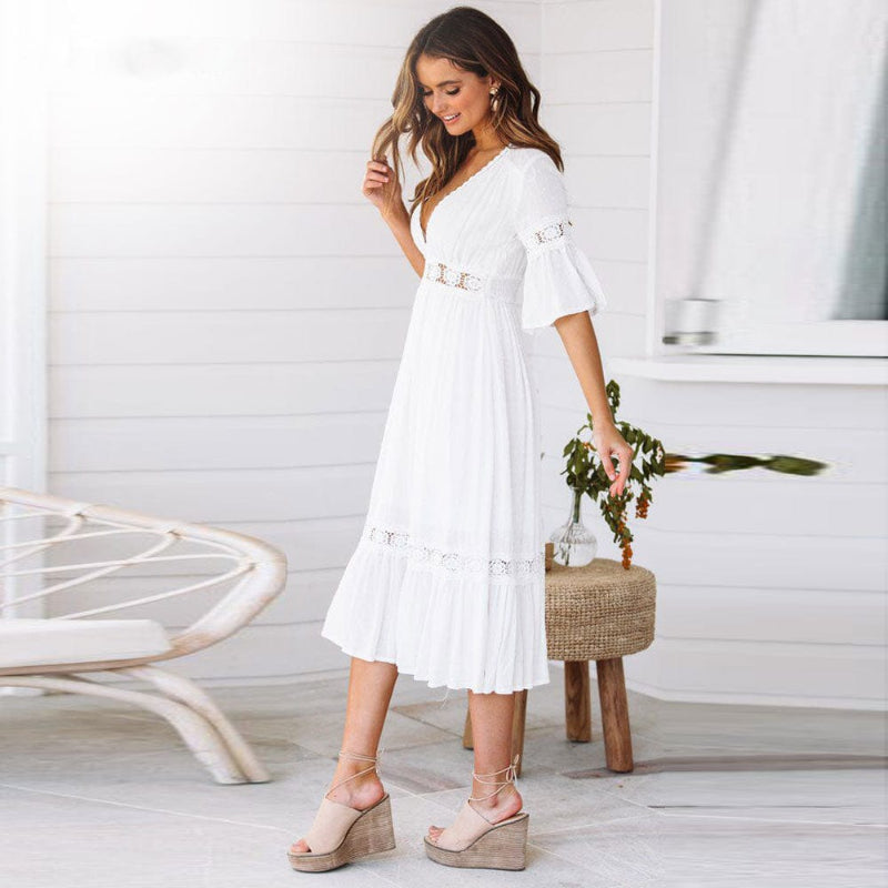 Female model in a flowing white V-neck midi dress against a plain background.