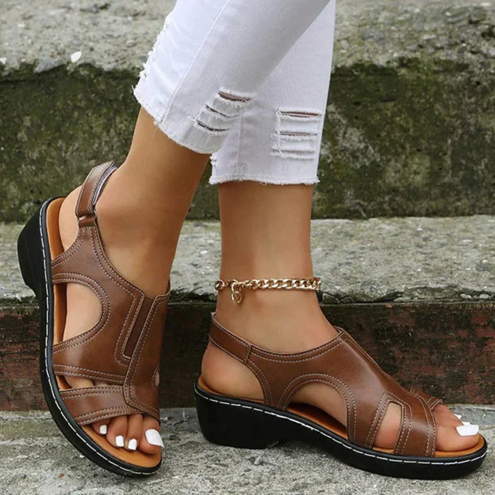 Female model wearing open toe sandals with adjustable straps on a plain background.
