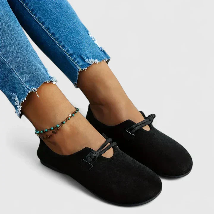Female model standing in polished loafers on a plain background.