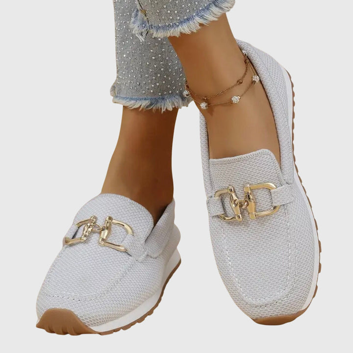 Woman modelling classic loafers on a plain background.