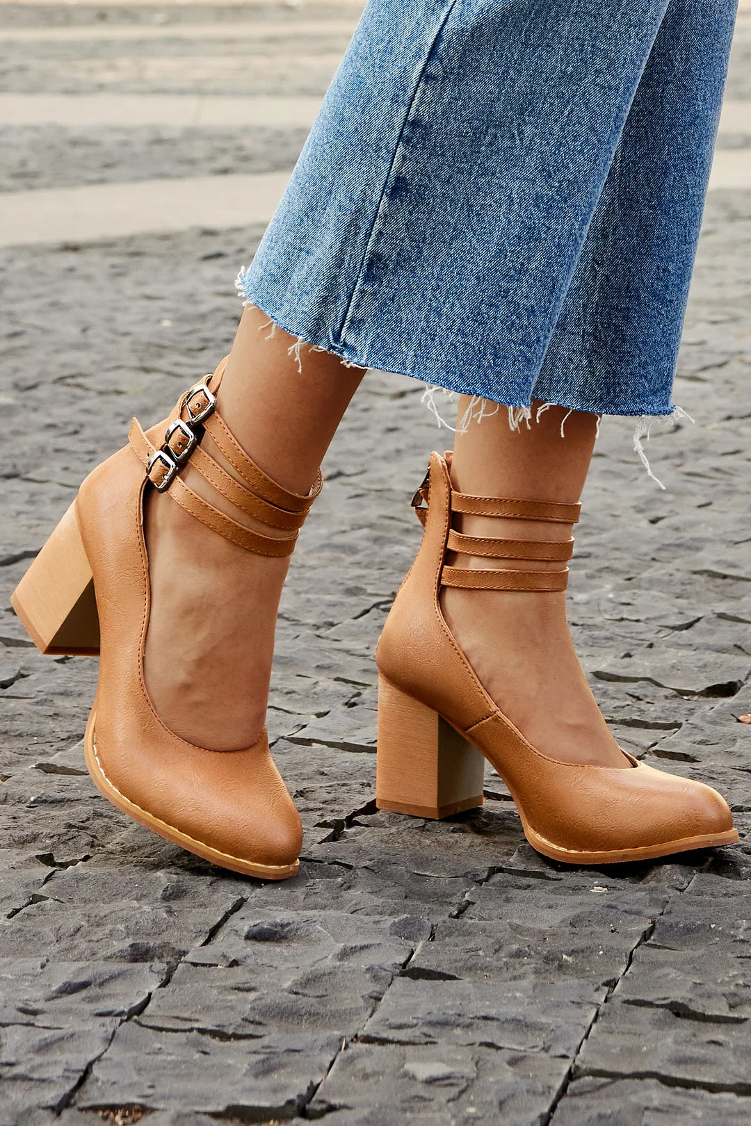 Woman wearing minimalist block heel sandals on a plain background.
