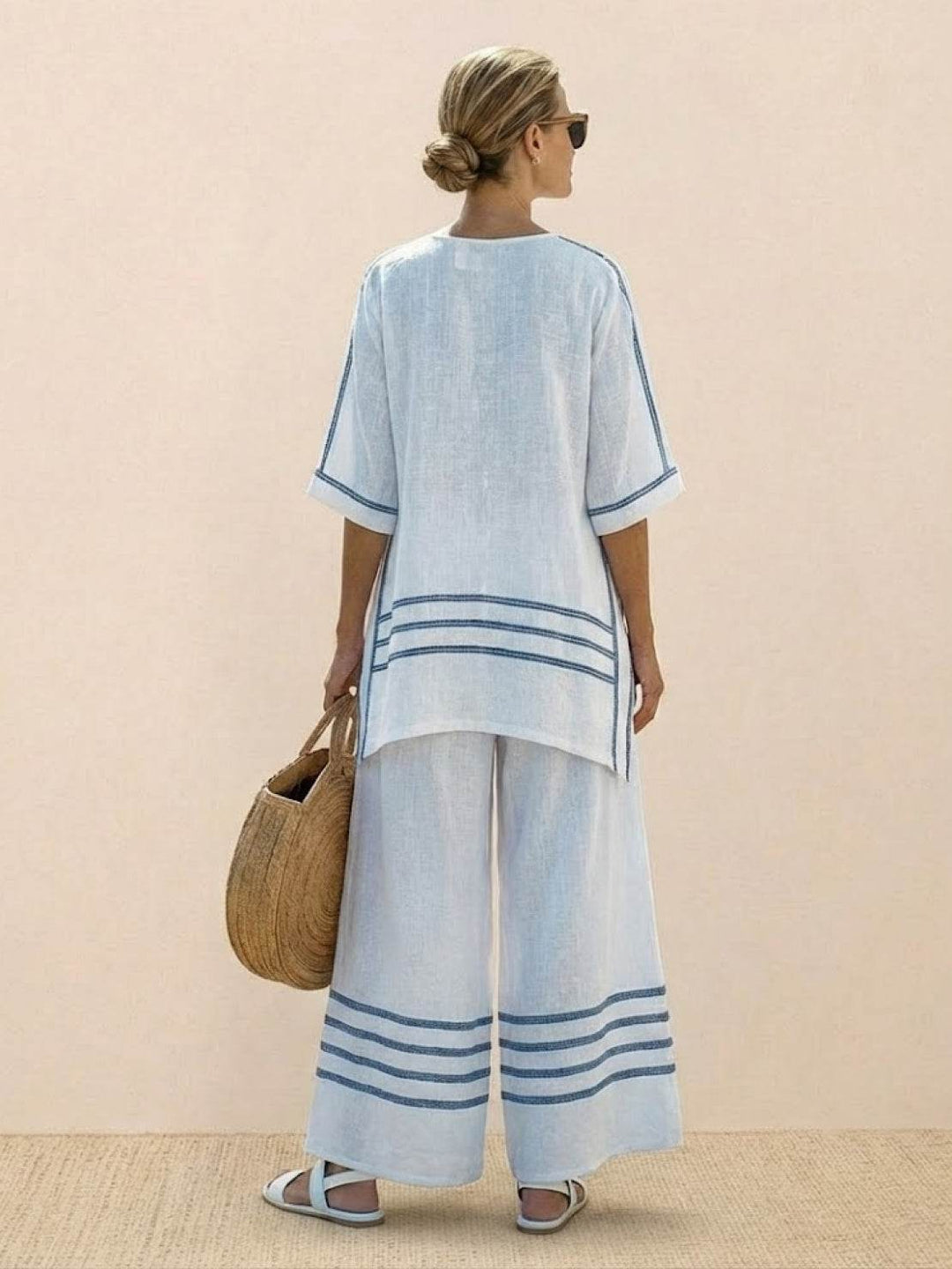 Female model wearing a longline embroidered tunic paired with flowing wide-leg trousers.