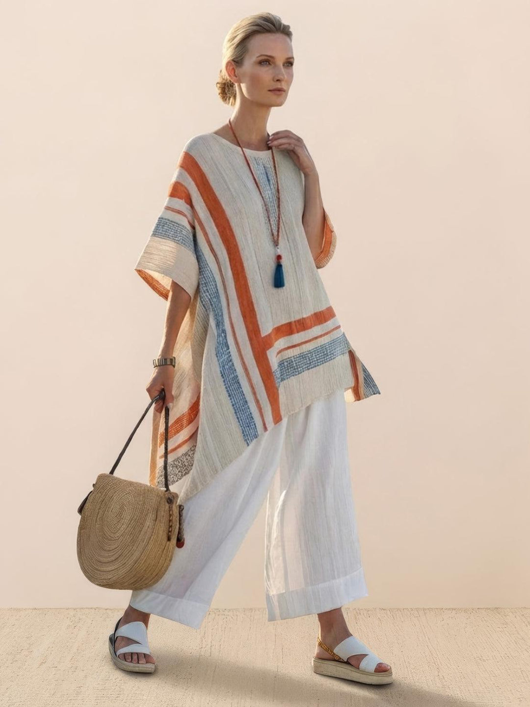 Woman wearing an embroidered tunic top paired with wide-leg trousers on a plain background.