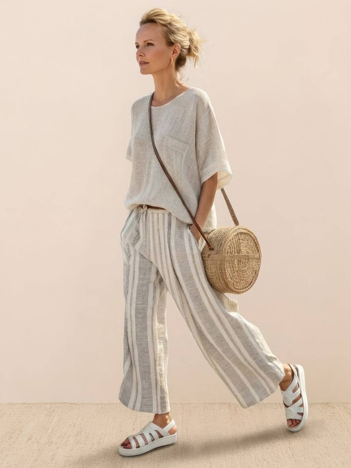 Female model wearing an embroidered two-piece outfit with a tunic top and wide-leg trousers against a plain background.