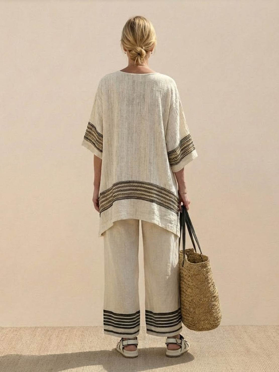 Female model wearing a striped two-piece outfit with decorative neckline and hem embroidery.