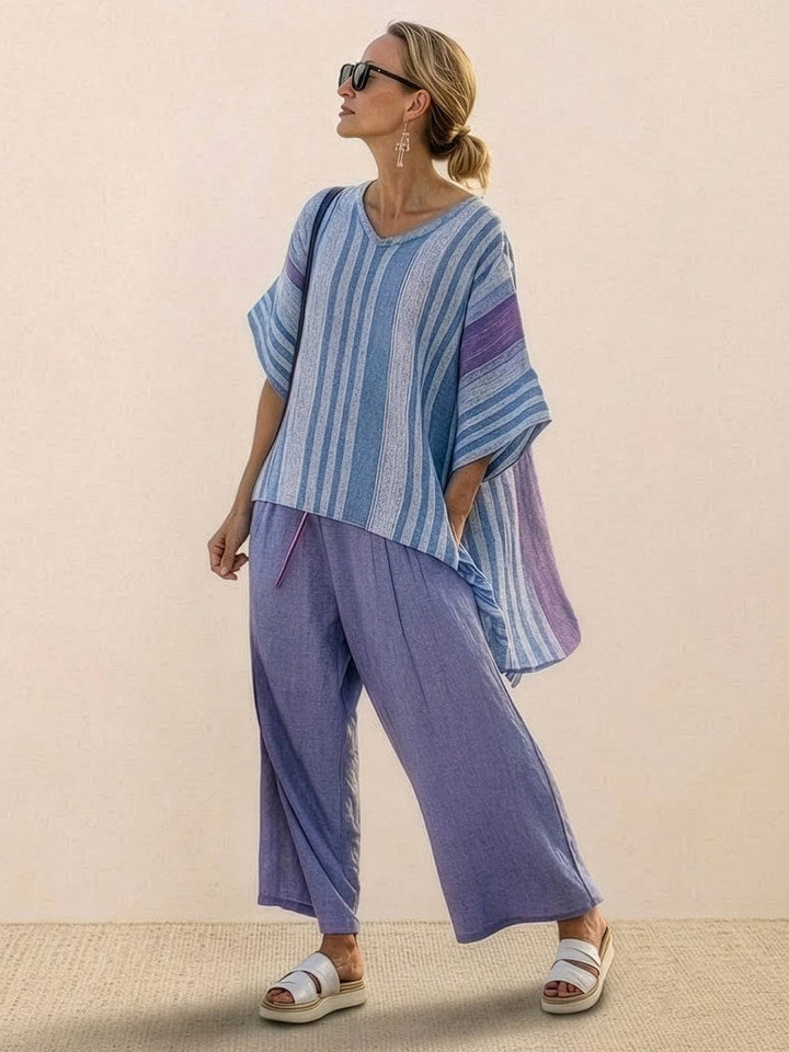 Woman wearing a relaxed striped outfit with floral embroidery on a plain background.