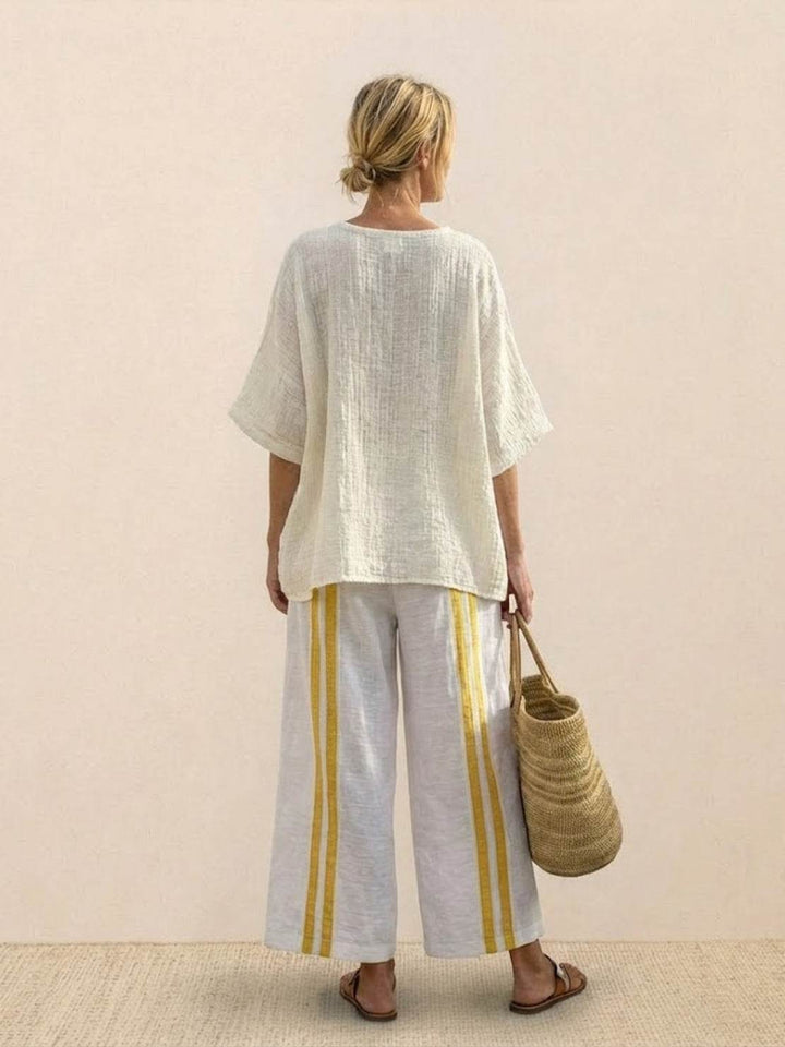 Female model showcasing an embroidered tunic top and relaxed trousers against a plain background.