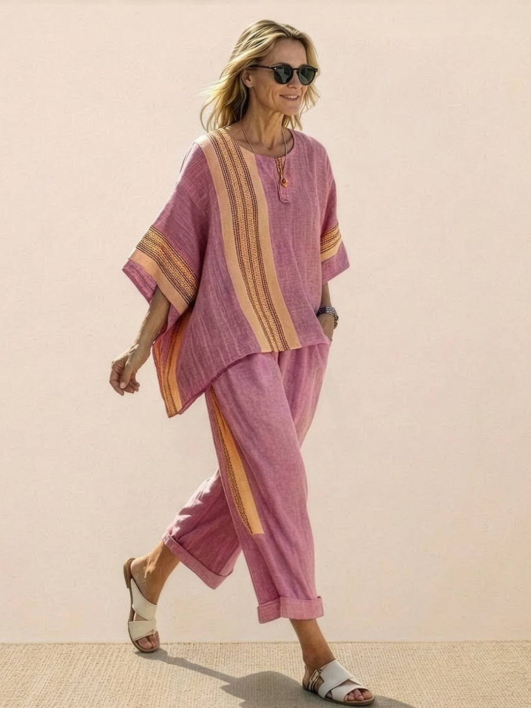 Woman in an embroidered tunic and matching trousers displayed against a plain backdrop.
