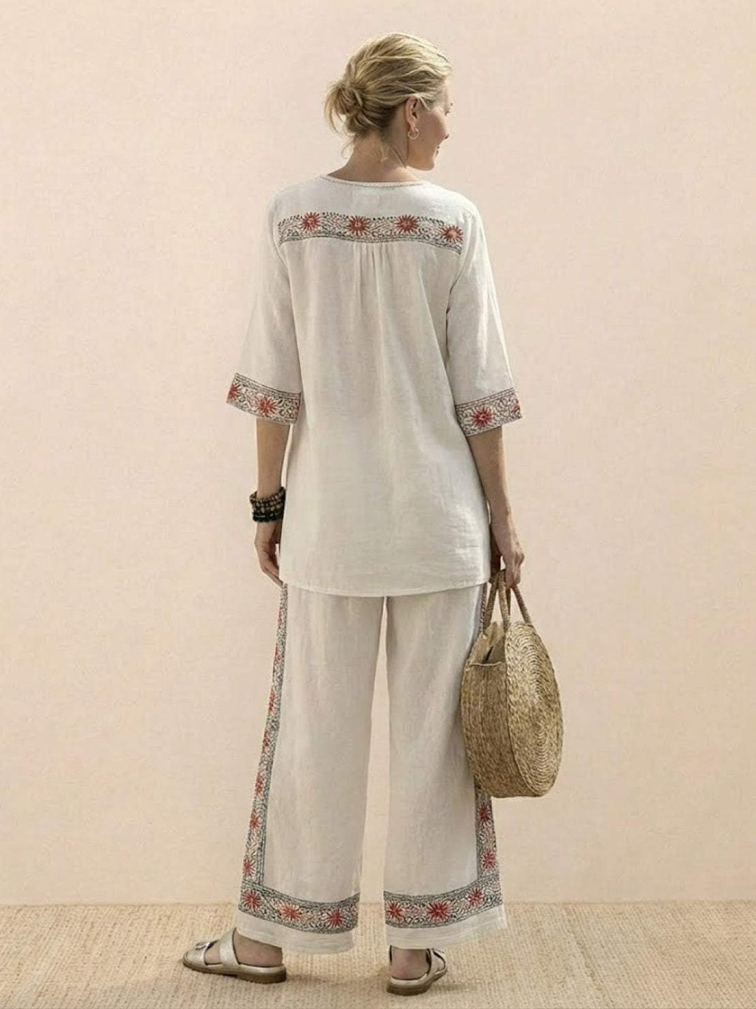 Woman wearing a coordinated two-piece outfit with decorative embroidery and wide-leg trousers.