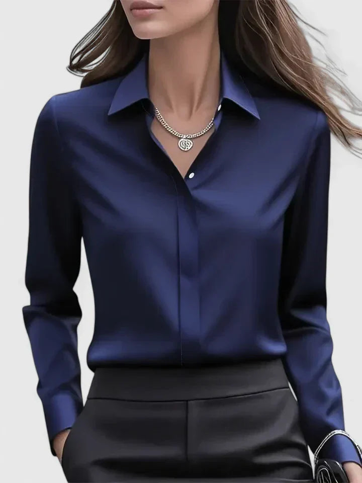 Woman wearing a satin button-down shirt with a pointed collar against a plain background.