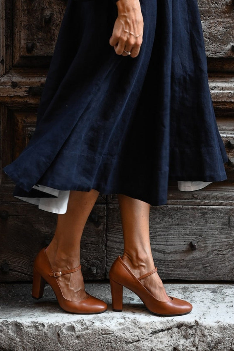 Brown sandal with chunky heel and adjustable strap on a plain background.