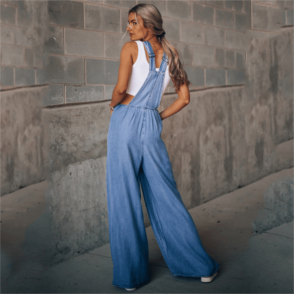 Female model showing a casual denim dungaree outfit on a plain background.