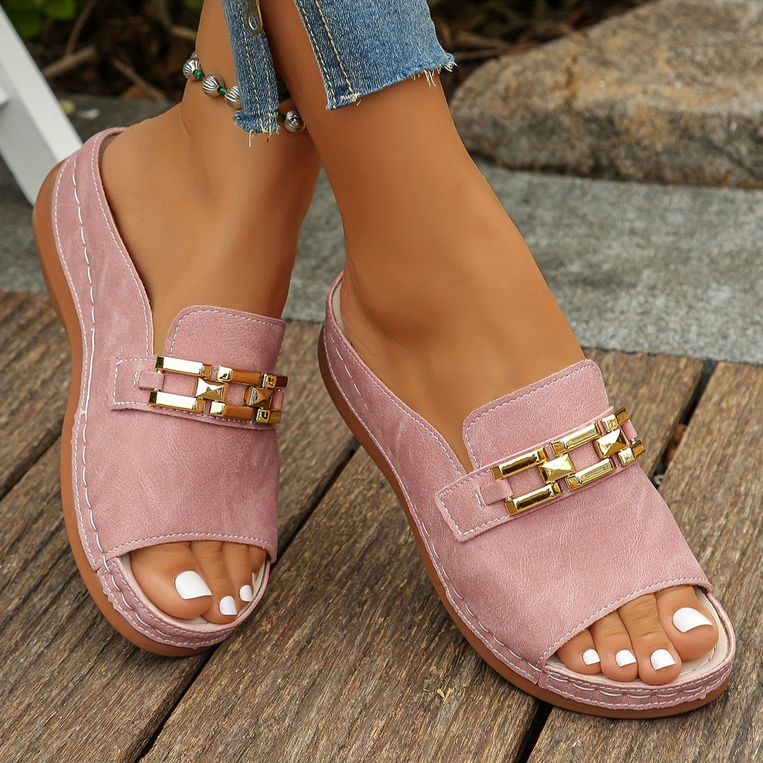 Woman wearing cushioned slide sandals with gold-link accents on a plain background.