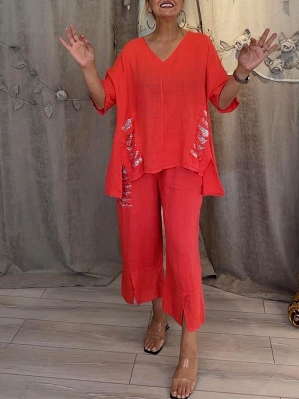 Female model showcasing a matching V-neck top and trousers set on a plain background.