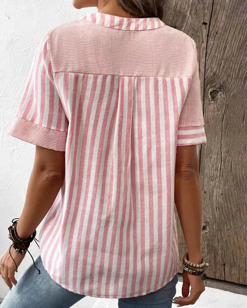  Woman in a vertical striped blouse with long sleeves on a plain background.