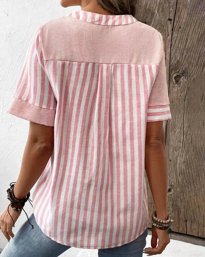  Woman in a vertical striped blouse with long sleeves on a plain background.