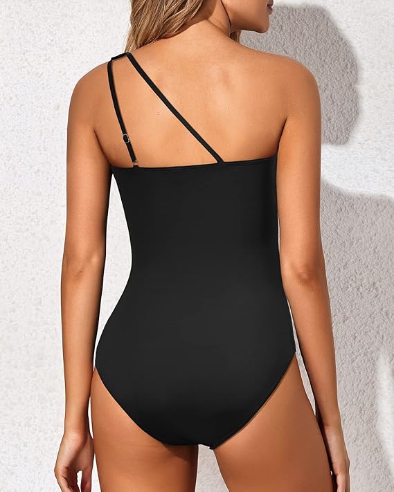 Model in an elegant asymmetrical bathing suit against a plain background.