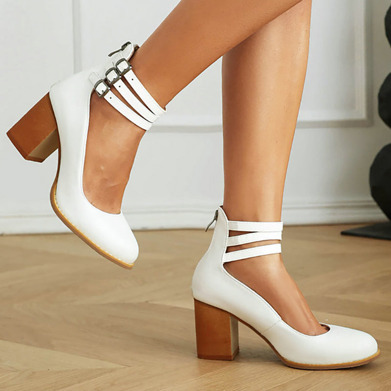 Woman standing in minimalist ankle strap sandals on a plain background.