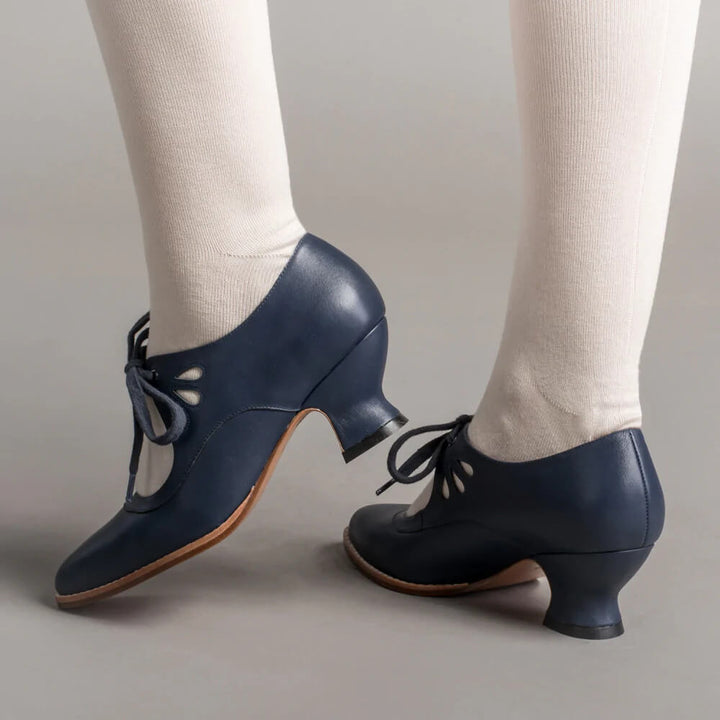 Female wearing elegant vintage style shoes against a plain background.