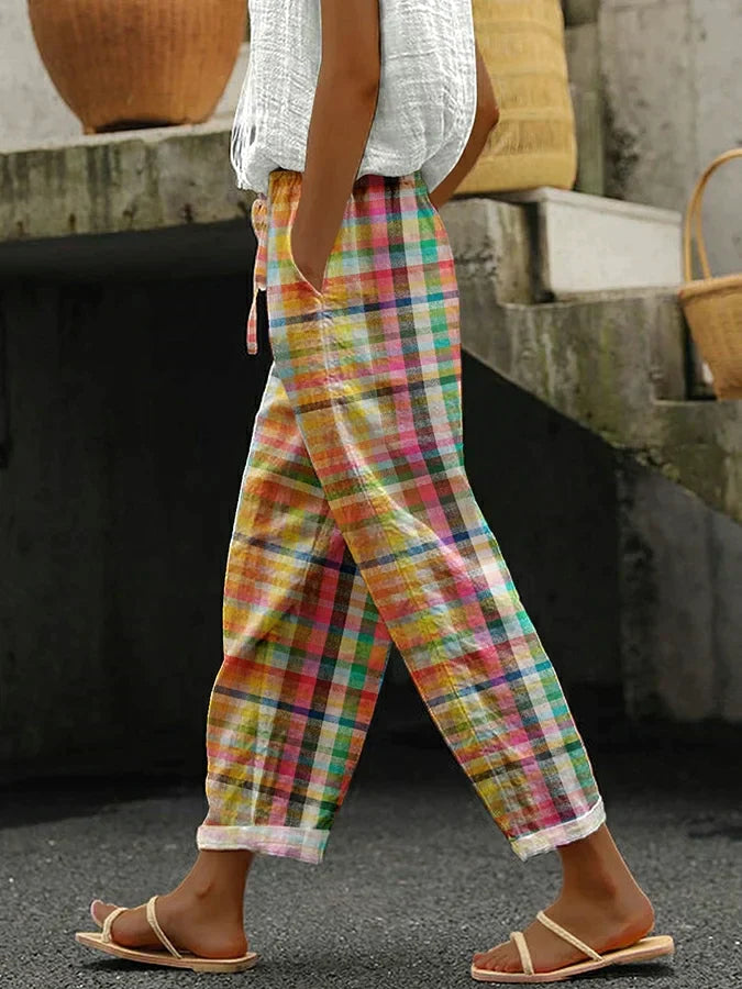 Female wearing checkered trousers with a relaxed fit on a plain background.