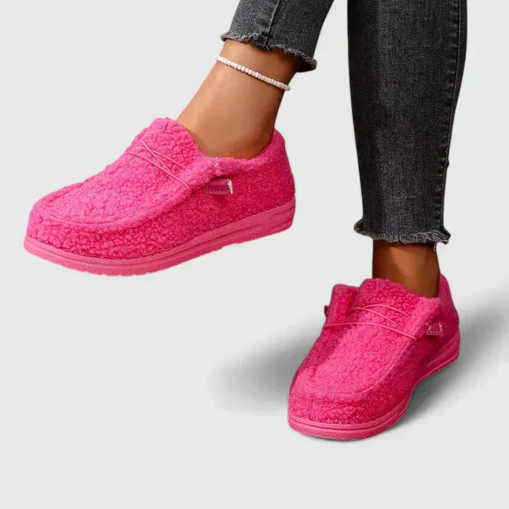 Female model showing polished loafers with a plain background.