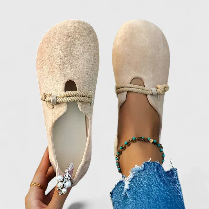 Female model styling slip-on footwear with a plain background.