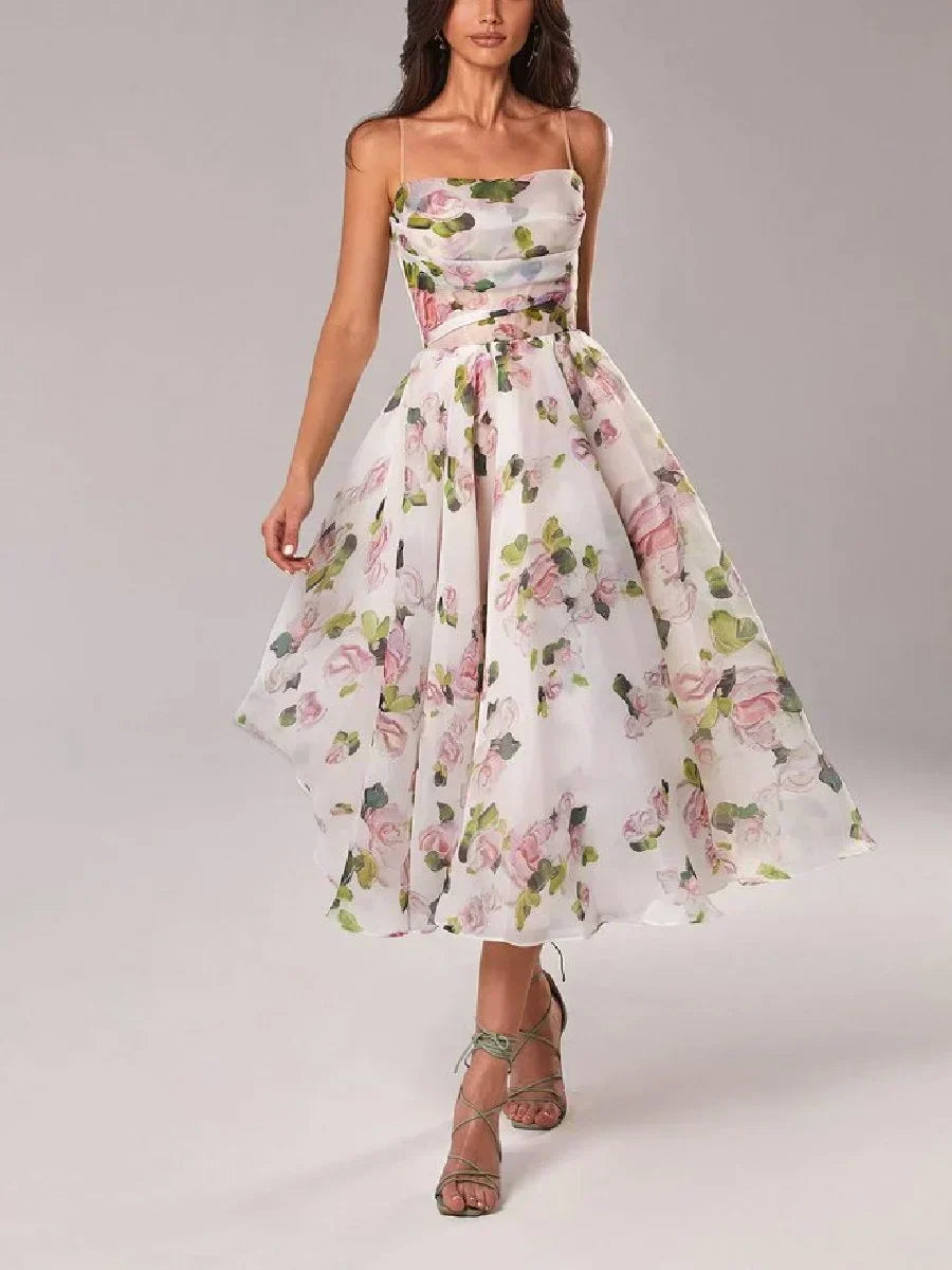 Woman wearing a floral midi dress with a fitted bodice and flowing skirt on a plain background.