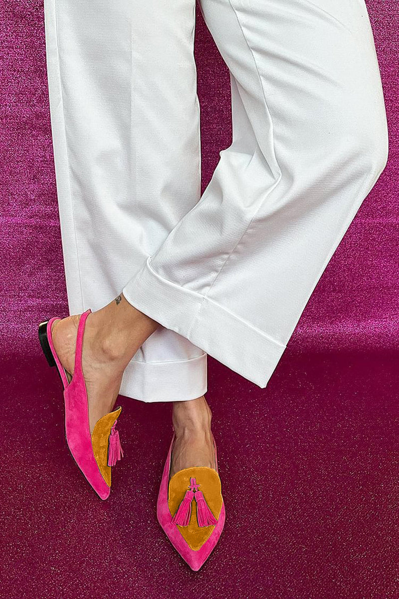 Statement flat shoes with vibrant fringe detail on a plain background.