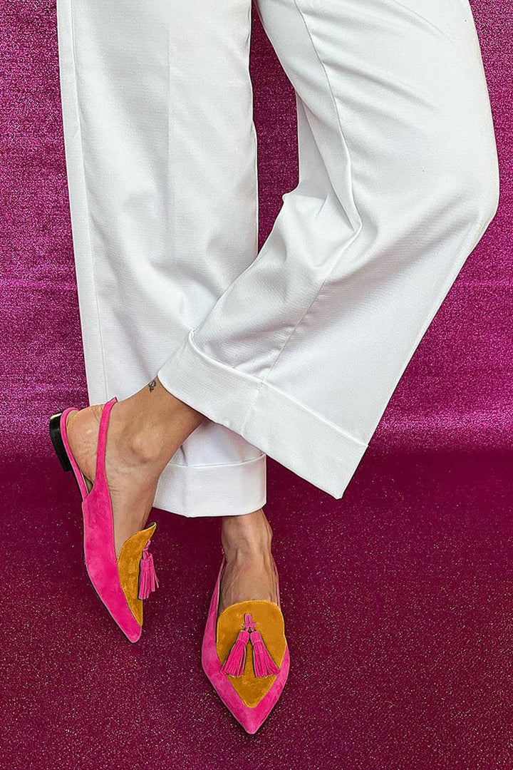 Statement flat shoes with vibrant fringe detail on a plain background.