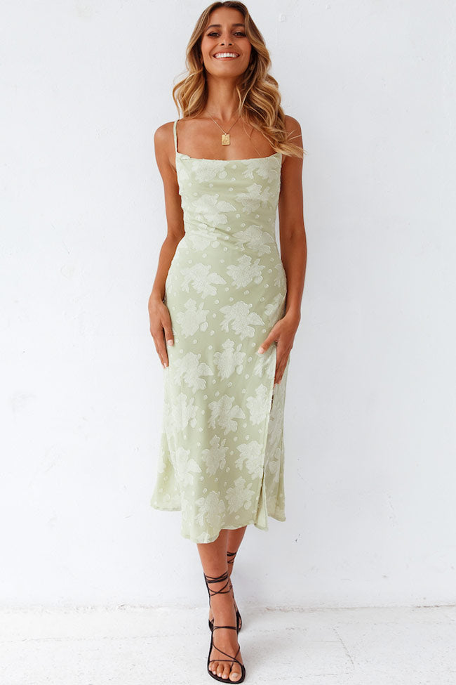 Woman wearing a floral high-slit midi dress on a plain background.