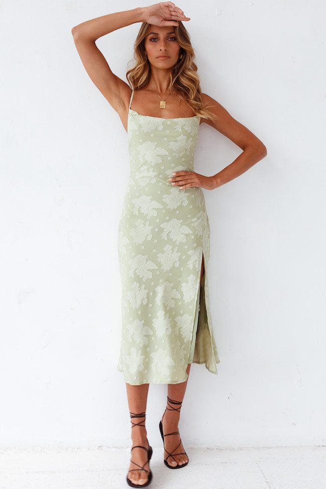  Female model showcasing a floral midi dress with a side slit on a plain background.