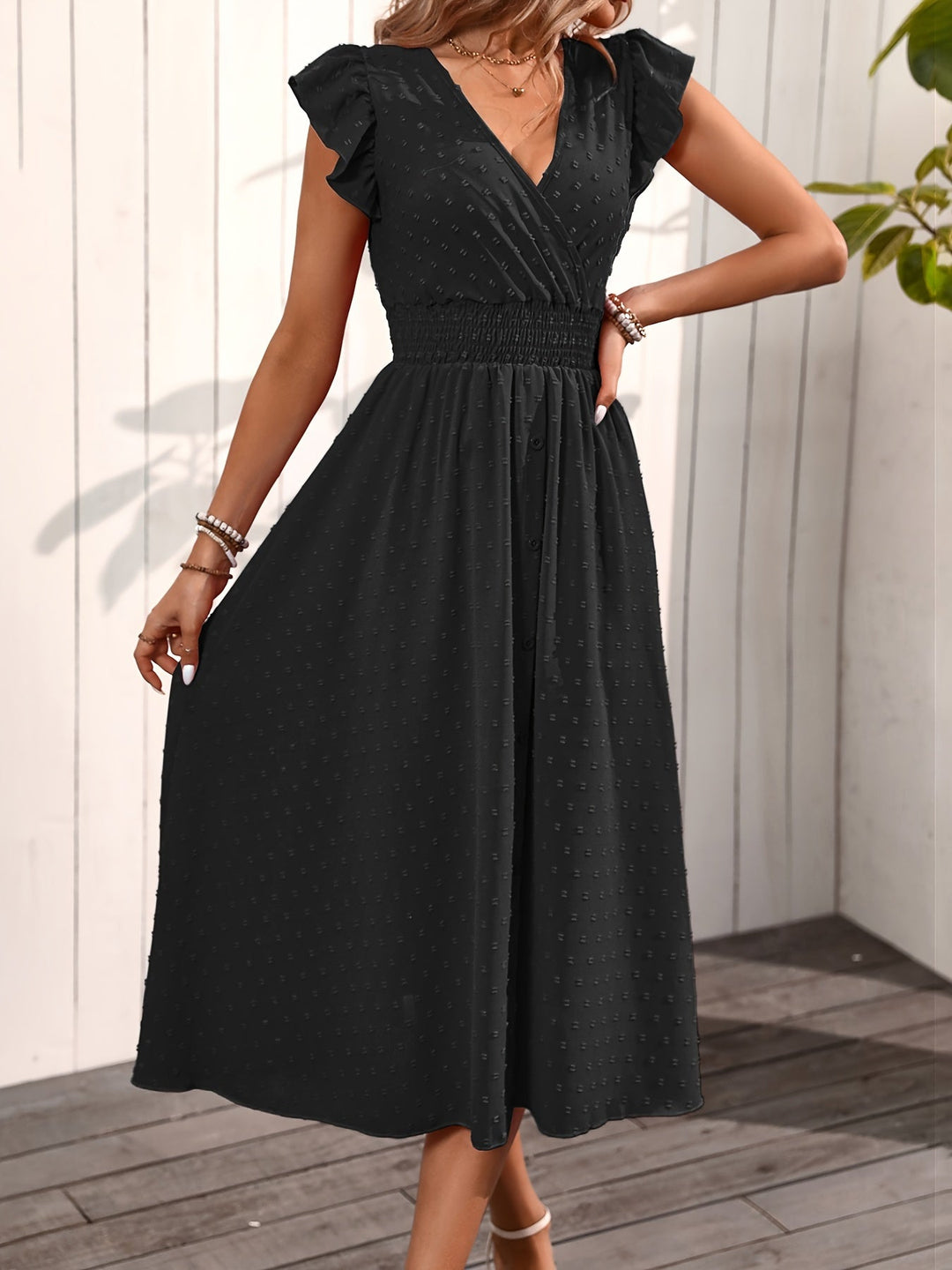  Woman in a ruffle sleeve dress with an elegant midi-length silhouette on a plain background.