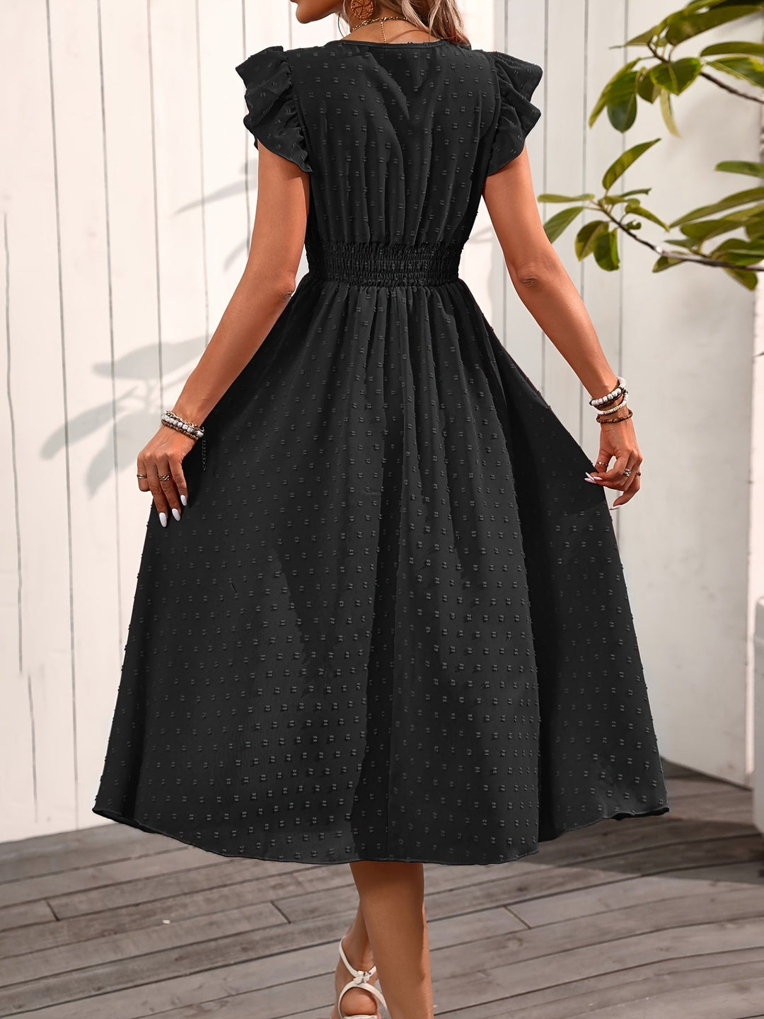 Woman in a ruffle sleeve midi dress with an elegant and versatile silhouette on a plain background.