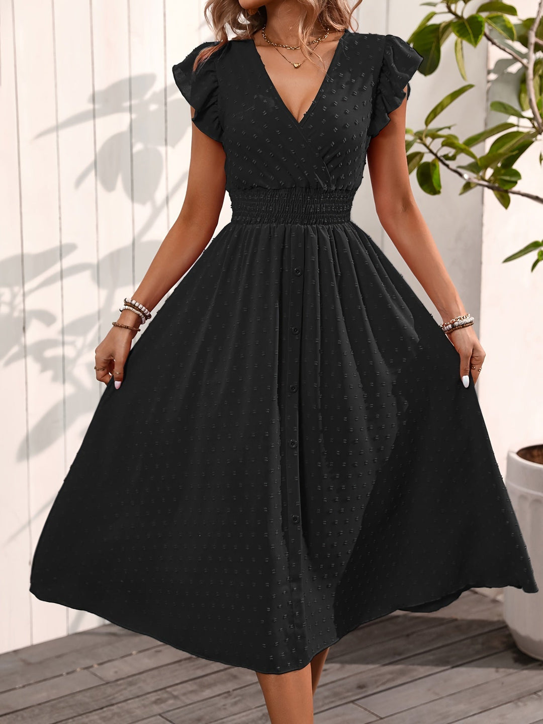  Female model displaying a stylish midi dress with a spotted design on a plain background.