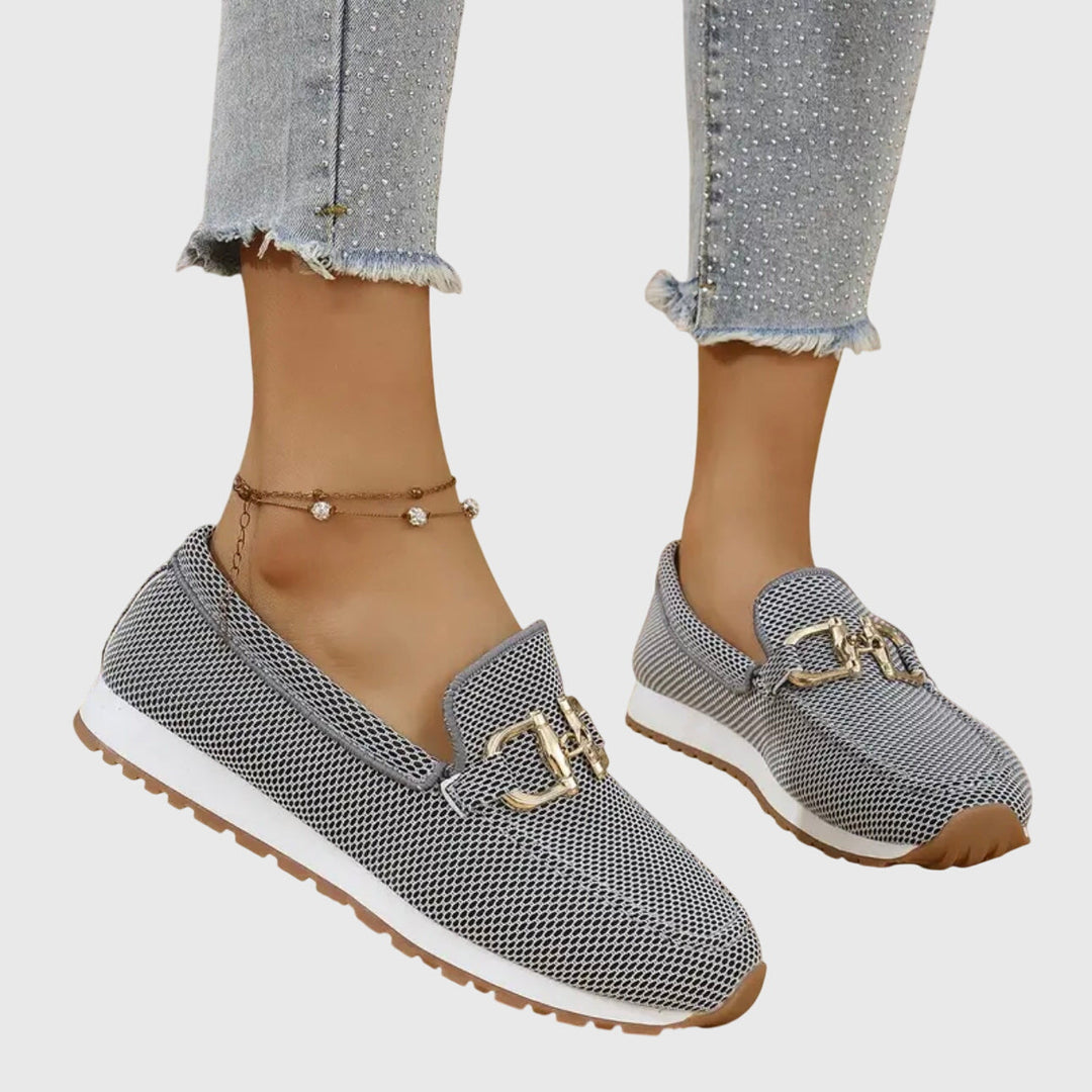 Female model showcasing casual loafers on a plain background.