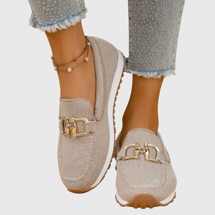 Female wearing stylish slip-on loafers on a plain background.