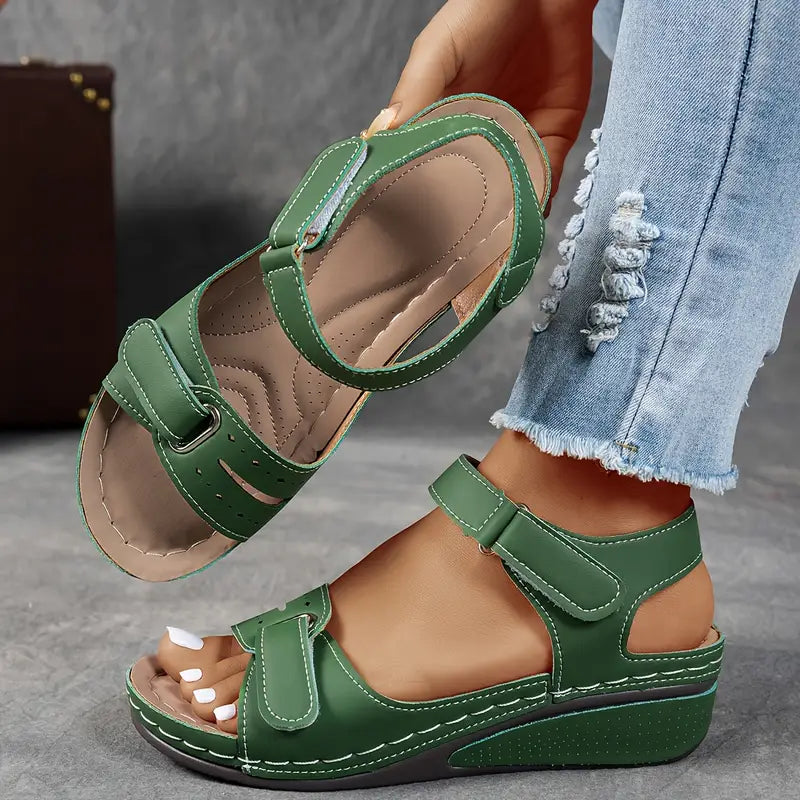 Female model standing in casual wedge sandals on a plain background.