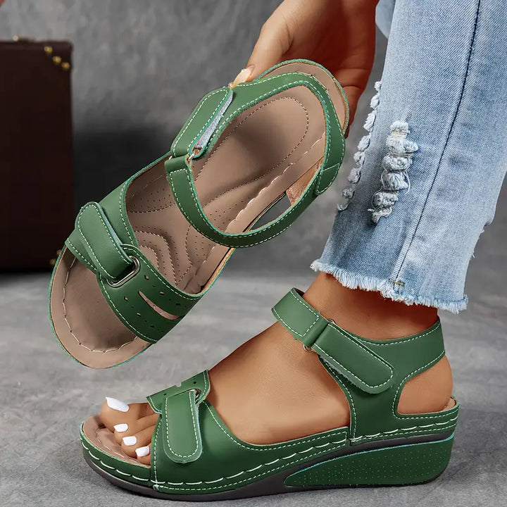 Female model standing in casual wedge sandals on a plain background.