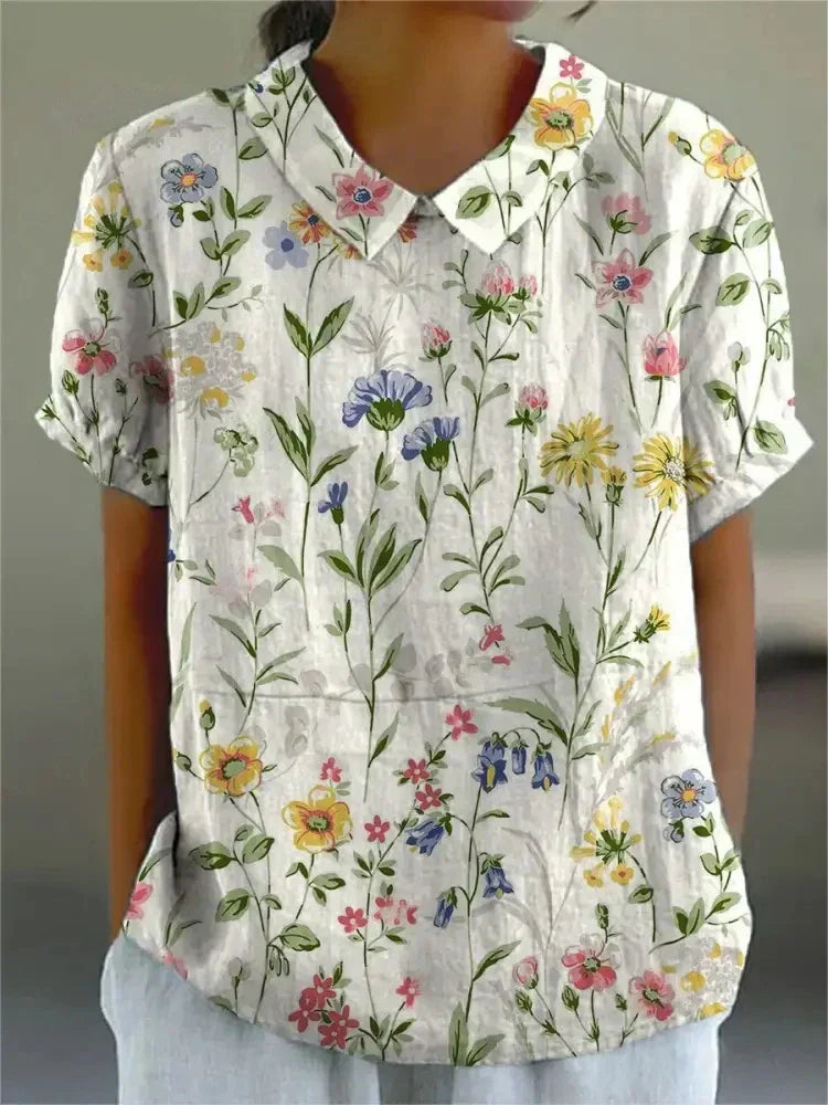  Female modelling a lightweight floral blouse with long sleeves on a plain background.