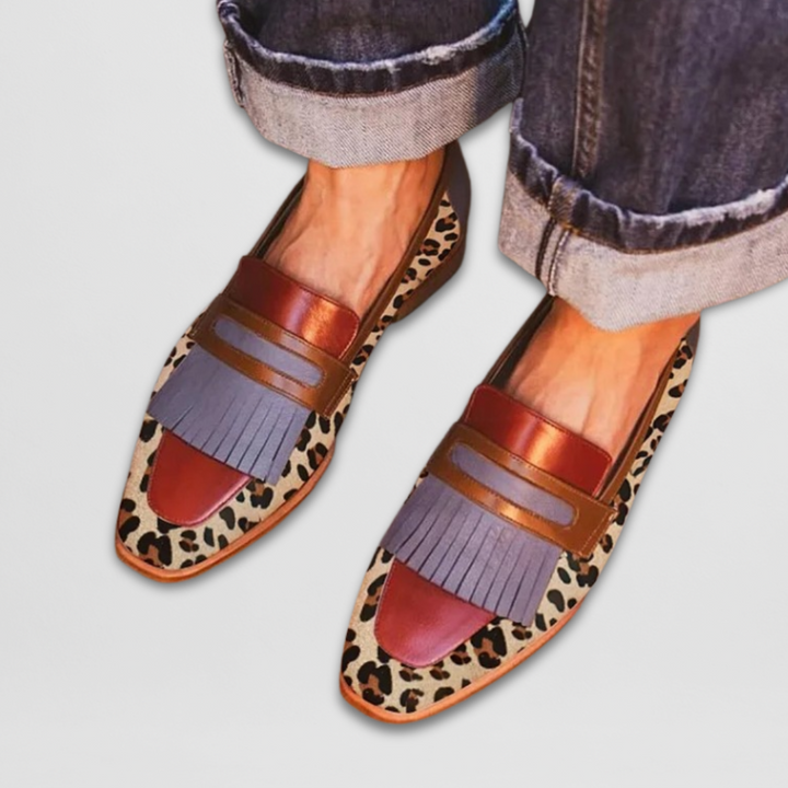 Woman showcasing sleek leather loafers against a plain background.