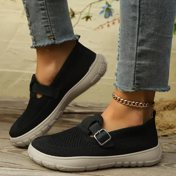 Woman standing in classic Mary Jane shoes with a plain background.