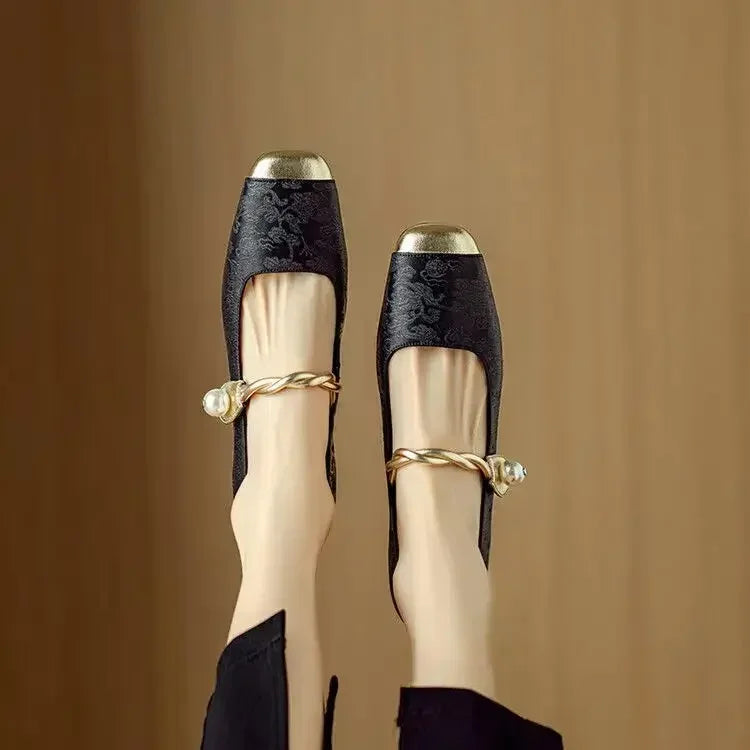 Female standing in square toe Mary Jane shoes with metallic front detail on a plain background.