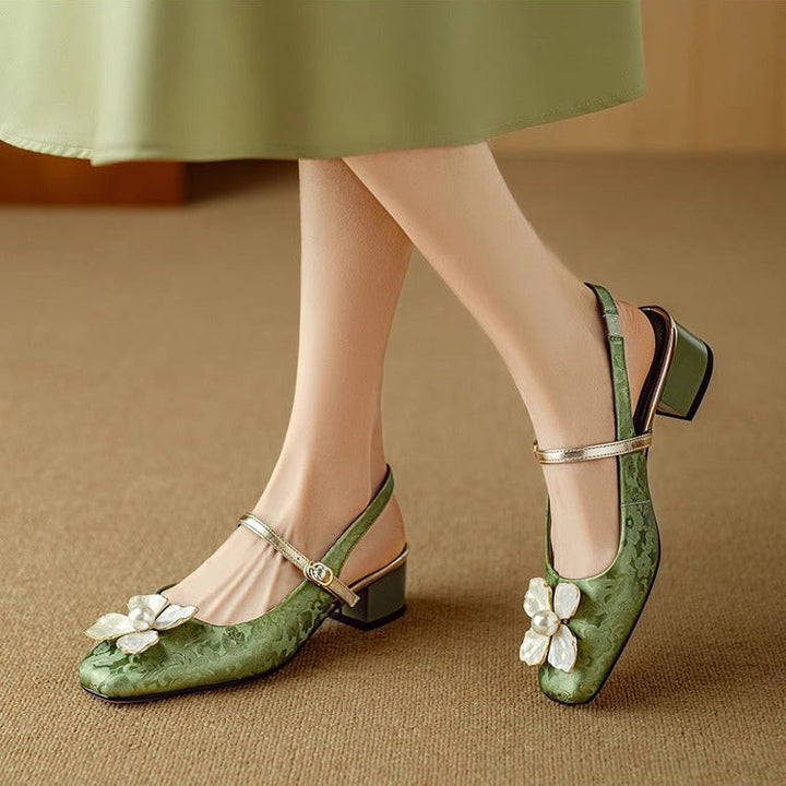 Female wearing floral slingback pumps on a plain background.