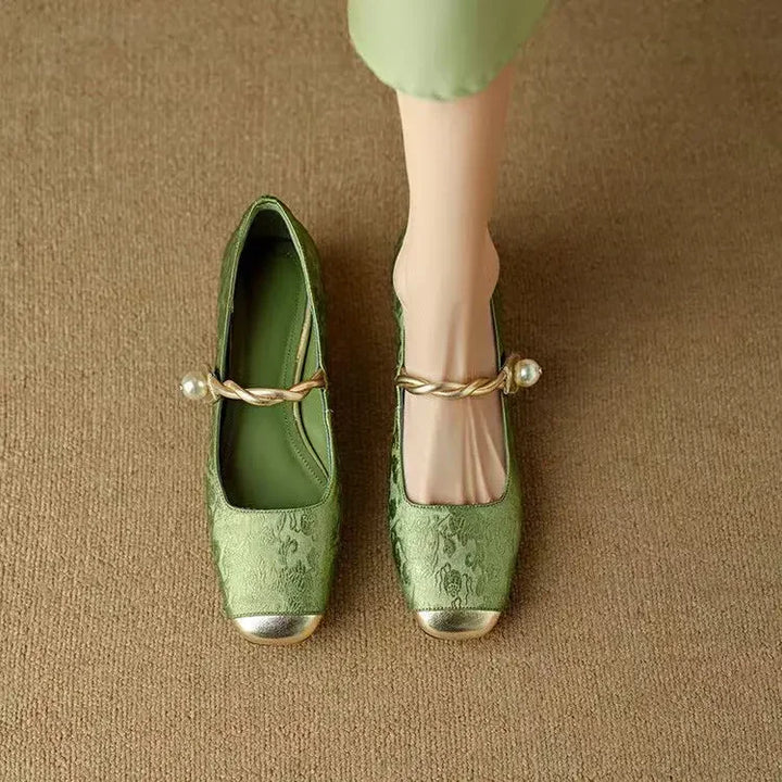 Female showcasing metallic toe cap Mary Jane shoes with a glitter heel on a plain background.