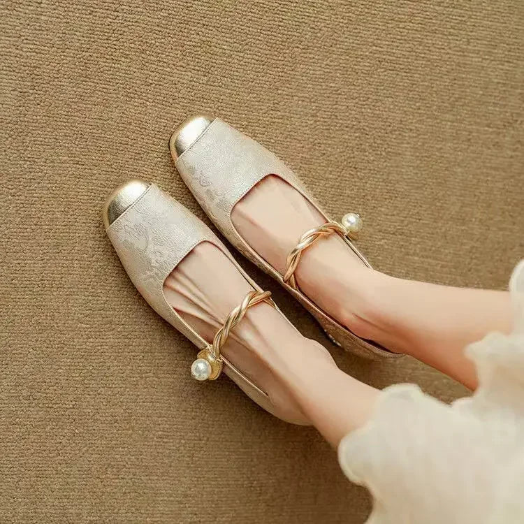 Woman styling dressy Mary Jane shoes with glitter heel detail on a plain background.