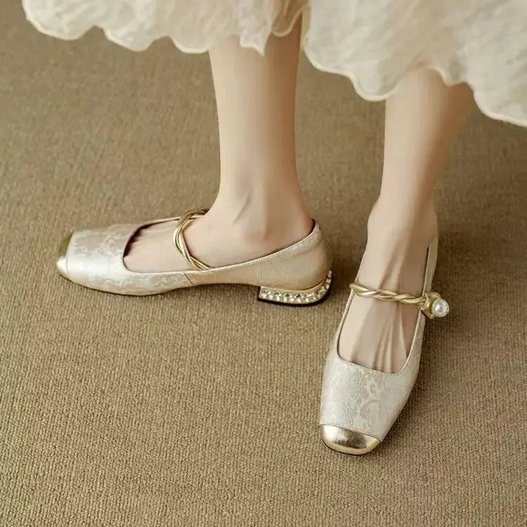Female wearing feminine pearl strap shoes with block heel styling on a plain background.