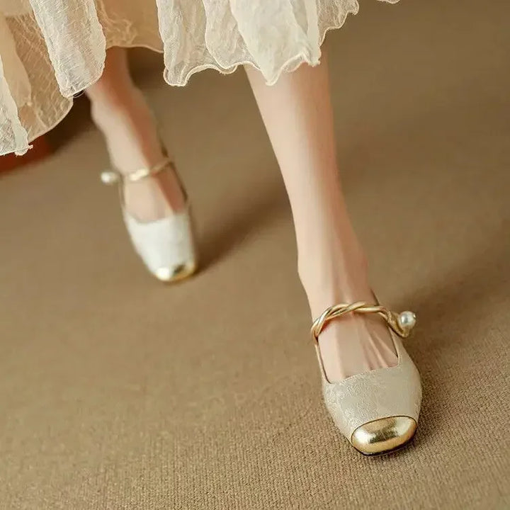 Female modelling vintage-style Mary Jane shoes with pearl detail on a plain 