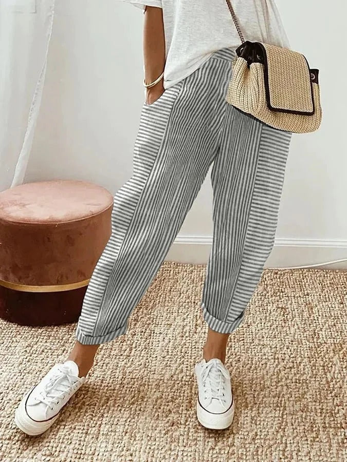 Woman wearing striped trousers paired with a simple top against a plain backdrop.
